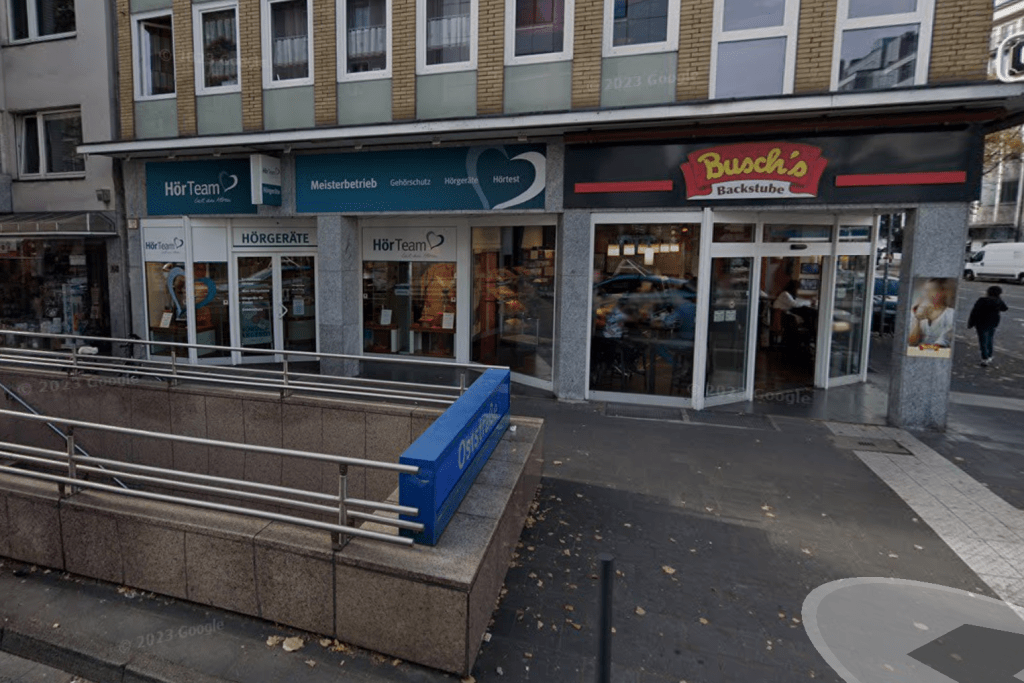 The photo shows two businesses on a street corner in Germany: one is a bakery, the other is an audiologist's.
