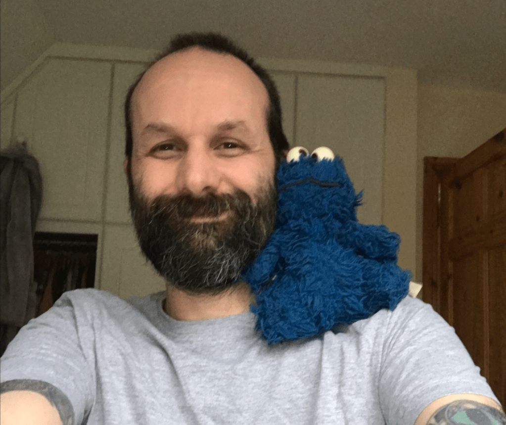 A photo of me with a slightly battered Cookie Monster toy on my shoulder.
